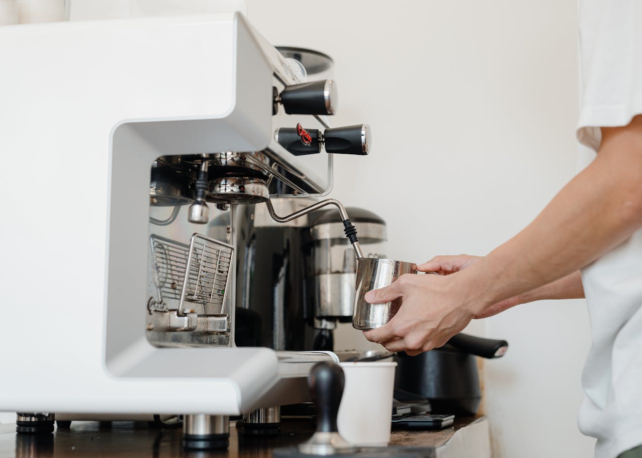 Close-up of a baristas hands using a coffee machine to make espresso indoors.