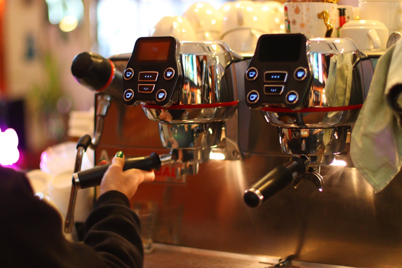 Barista using a professional espresso machine to craft a coffee brew indoors.